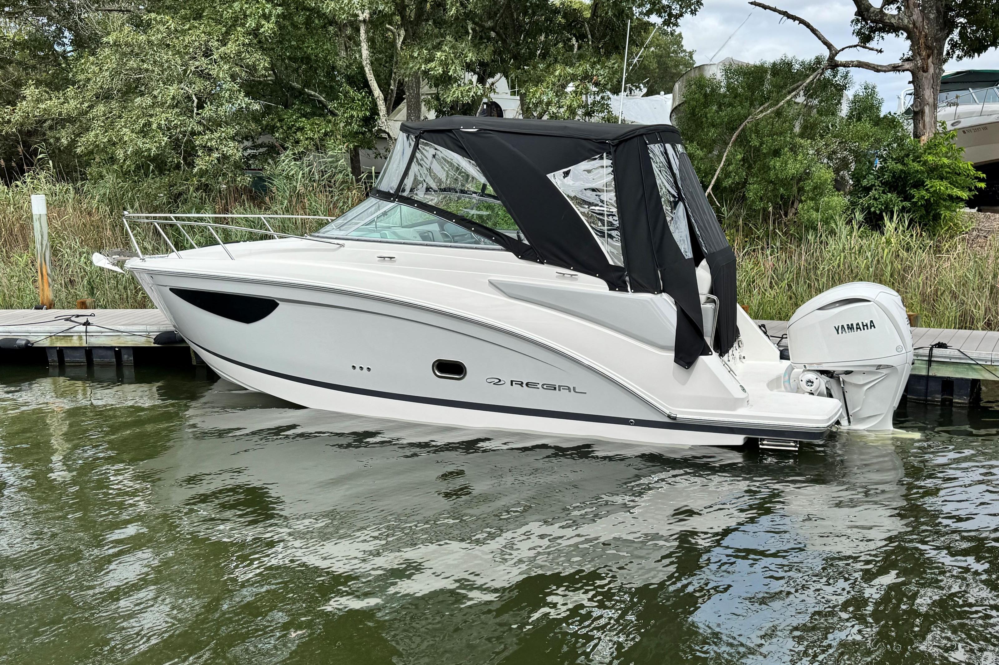 2026 Regal 26 XO boat docked with Yamaha outboard, featuring sleek design and black canopy.
