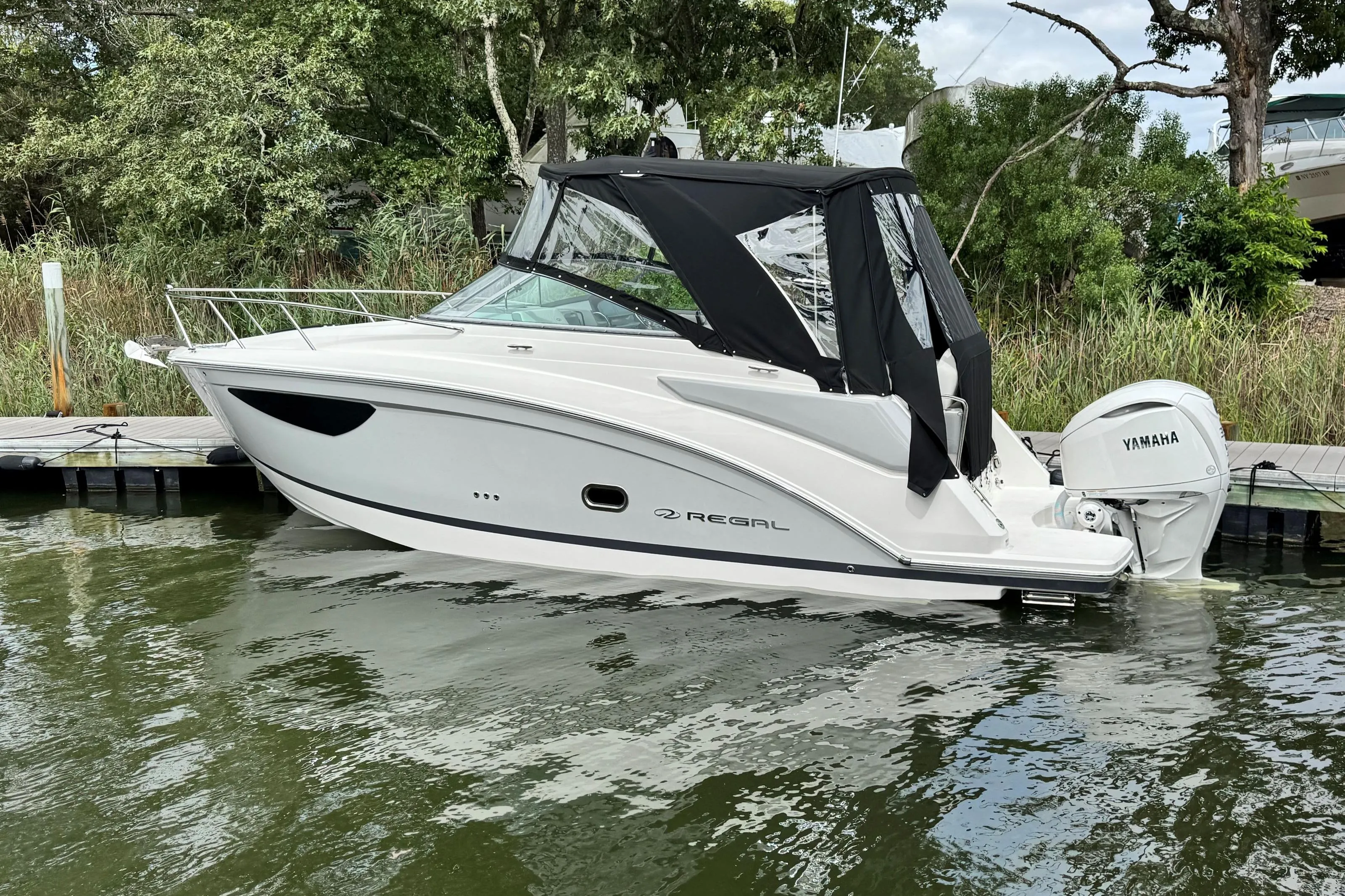 2026 Regal 26 XO boat docked with Yamaha outboard, featuring sleek design and black canopy.