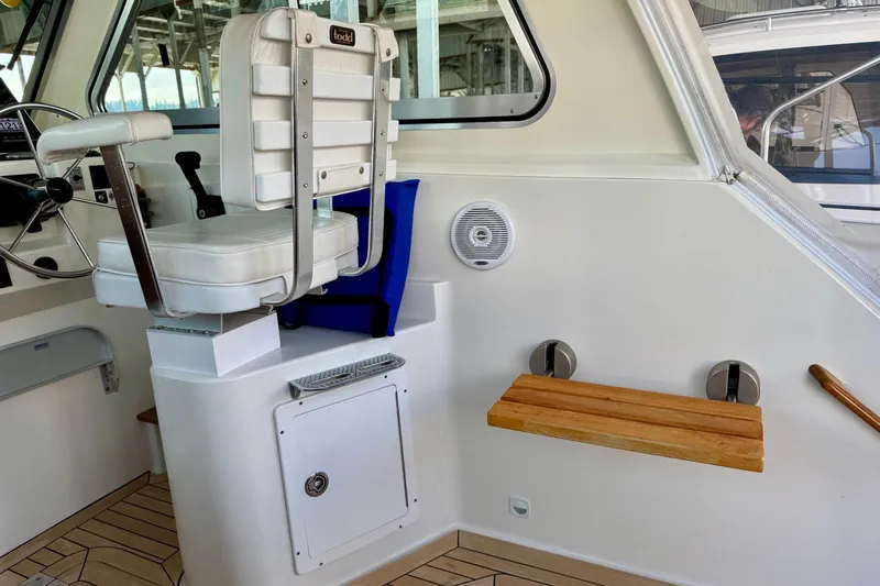 Tui Yacht Photos Pics 2005 Back Cove 29 boat interior with captain's chair and wooden fold-down seat.