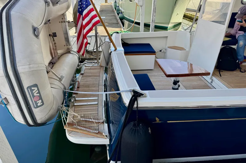 Tui Yacht Photos Pics 2005 Back Cove 29 boat with American flag, docked, featuring seating and wooden table.