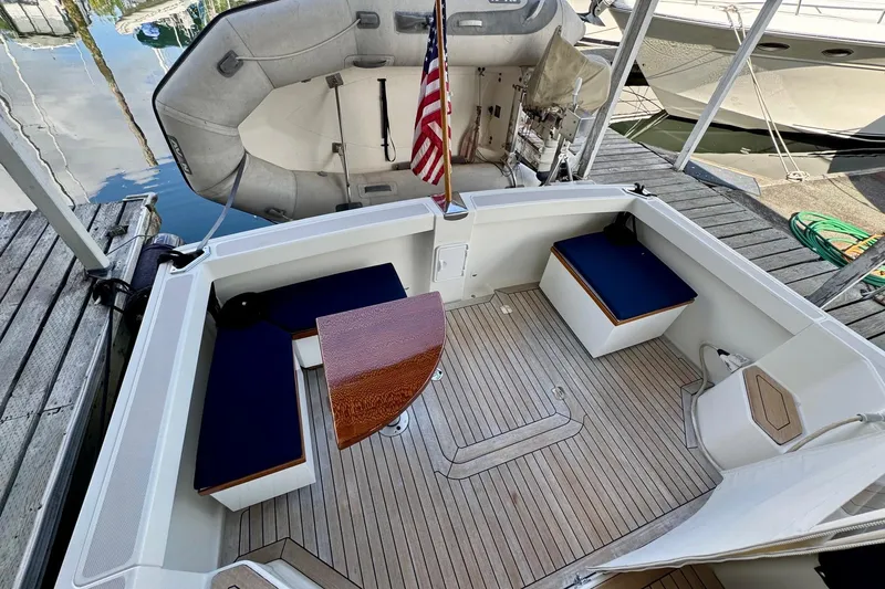 Tui Yacht Photos Pics 2005 Back Cove 29 boat deck with seating, wooden table, and American flag.