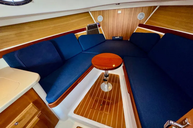 Tui Yacht Photos Pics Interior of 2005 Back Cove 29 boat with blue seating and wooden table.