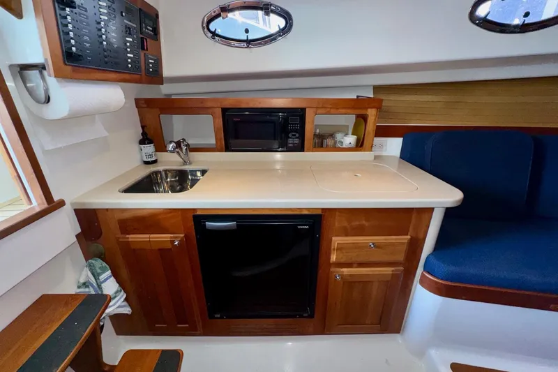 Tui Yacht Photos Pics 2005 Back Cove 29 interior with kitchenette, sink, microwave, and seating area.