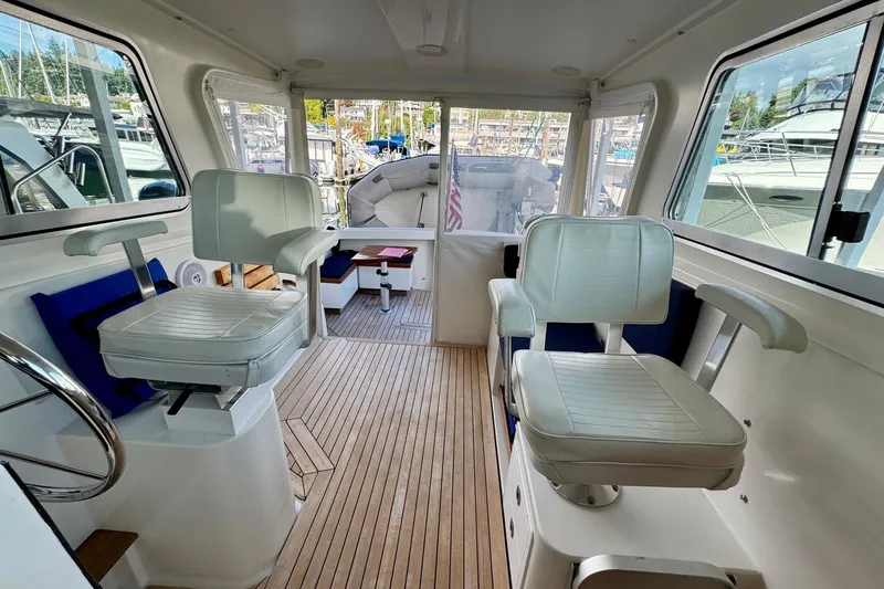 Tui Yacht Photos Pics Interior of 2005 Back Cove 29 boat with helm chairs and wooden flooring.