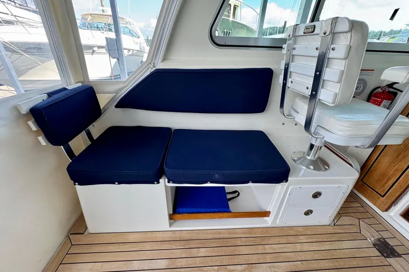 Tui Yacht Photos Pics 2005 Back Cove 29 boat interior with blue cushioned seating and wooden flooring.