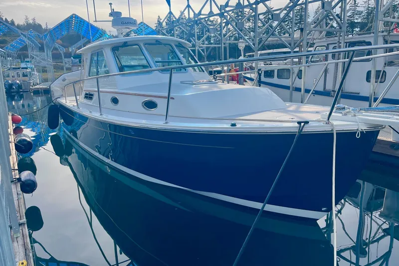 Tui Yacht Photos Pics 2005 Back Cove 29 boat docked in a marina, reflecting on calm water.