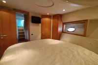 Luxurious cabin interior of 2010 Pershing 56 yacht with cozy bed and porthole.