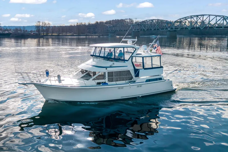  Yacht Photos Pics 1994 Tollycraft 45 Cockpit Motor Yacht cruising on a scenic river with a bridge backdrop.