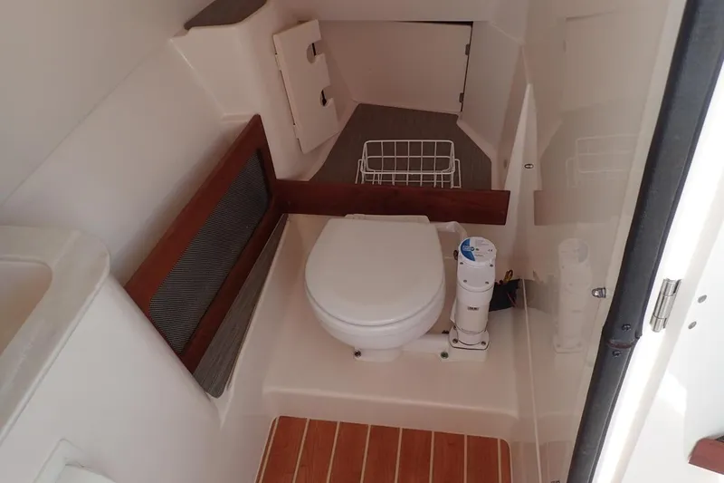  Yacht Photos Pics 2021 Grady-White Freedom 285 boat interior with compact marine toilet and wooden flooring.