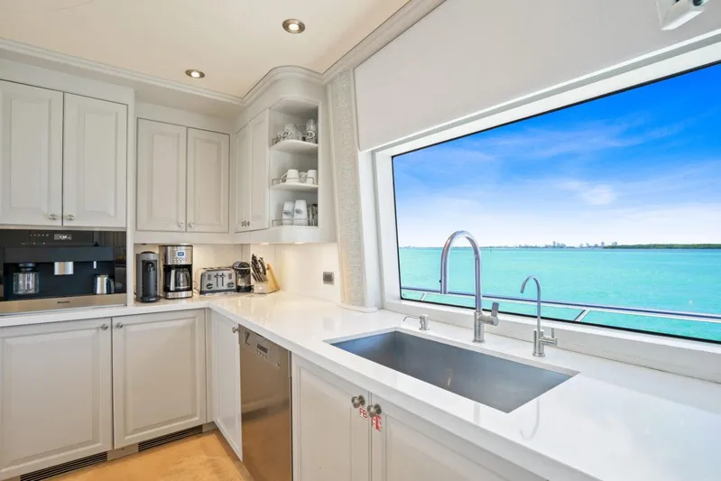 Risk And Reward Yacht Photos Pics Luxurious yacht kitchen with ocean view, featuring modern appliances and sleek white cabinetry.