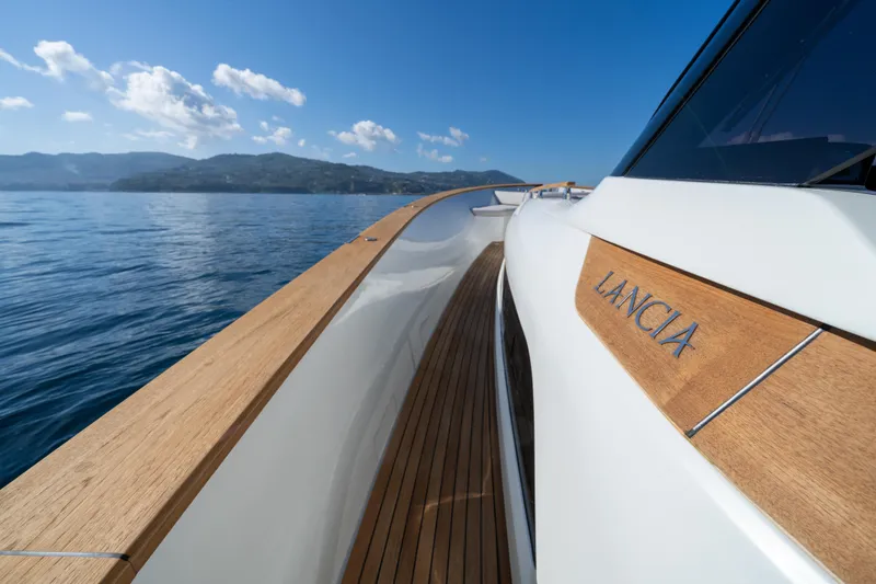 Viviendo Yacht Photos Pics 2024 Lancia Aprea 52 yacht on serene blue waters, showcasing elegant wooden deck.