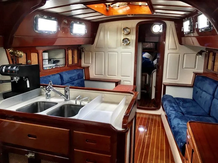 Light Reign Yacht Photos Pics Interior of 2000 Cherubini Schooner with wood finish, blue seating, and kitchen area.