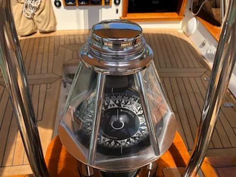 Light Reign Yacht Photos Pics Compass on Cherubini Schooner 2000, wooden deck, nautical navigation instrument.