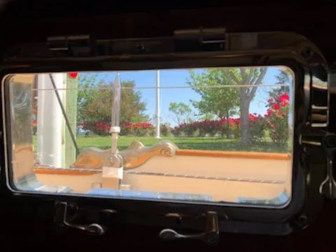 Light Reign Yacht Photos Pics View through a Cherubini Schooner 2000 porthole, showcasing a garden with trees and flowers.