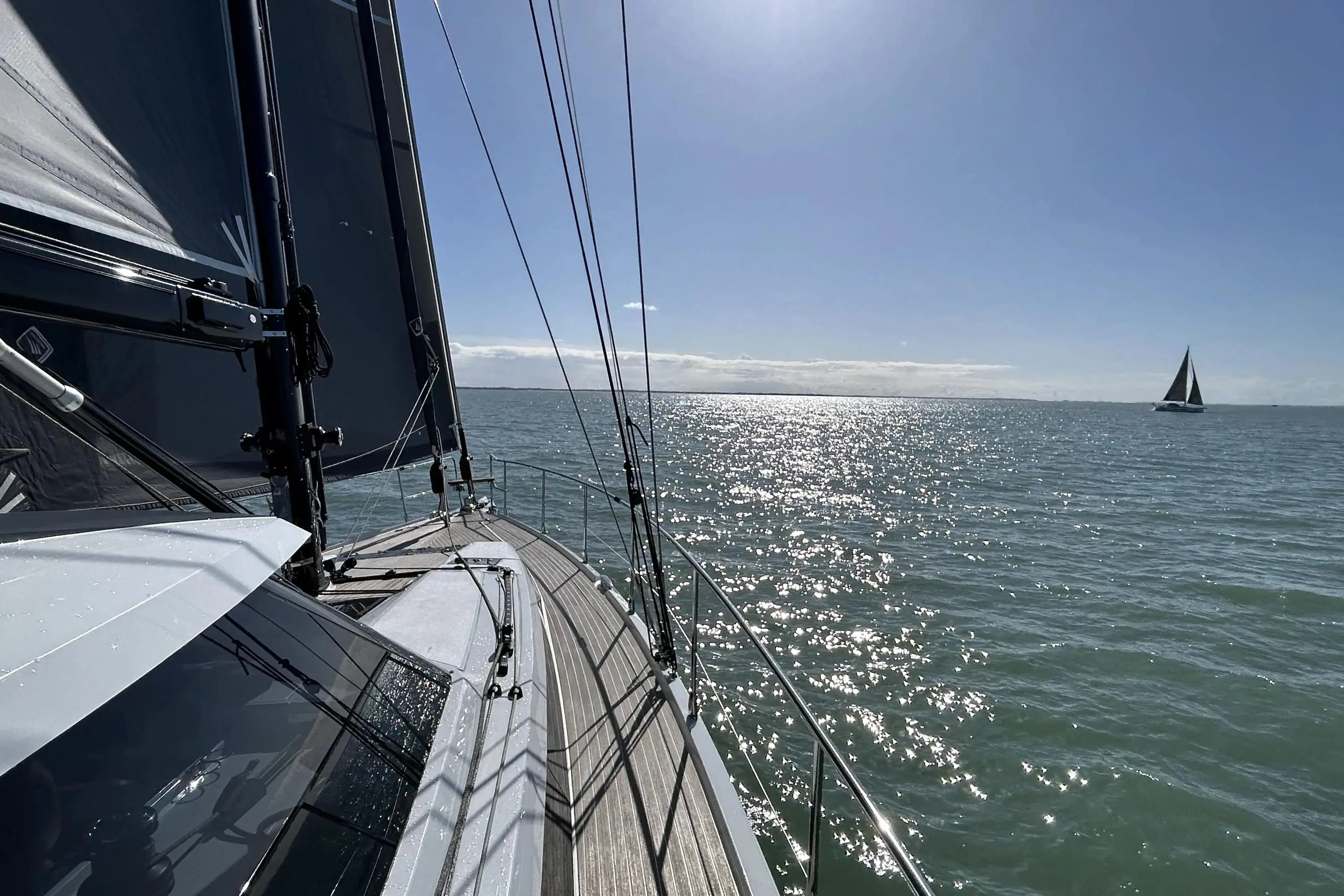 Sailing on a 2025 Amel 50 yacht under clear blue skies and sparkling sea.