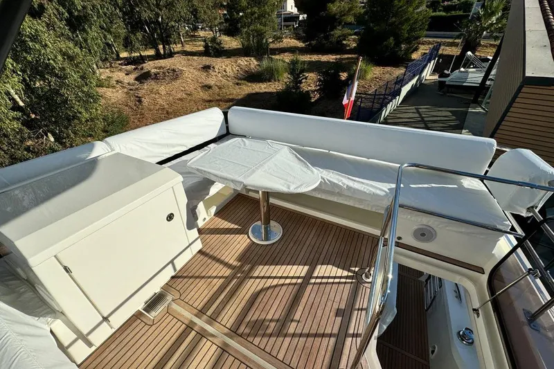  Yacht Photos Pics Prestige F4.9 yacht deck, 2026 model, featuring seating and table, surrounded by trees.