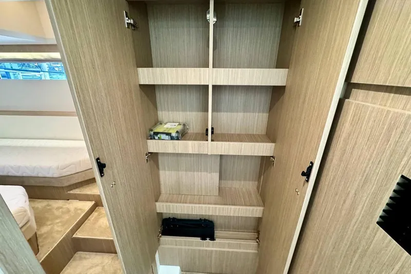  Yacht Photos Pics Open wooden cabinet with shelves inside a Prestige F4.9, 2026 model yacht interior.