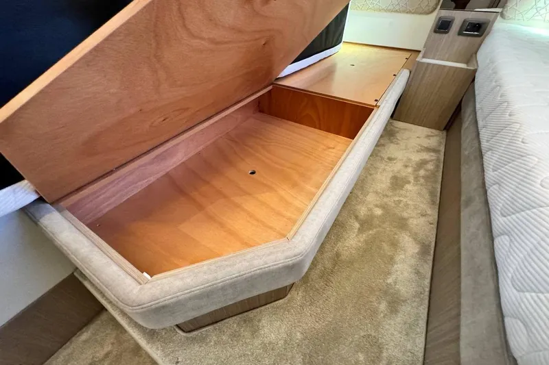  Yacht Photos Pics Under-bed storage compartment in a 2026 Prestige F4.9, featuring wooden interior and carpeted floor.