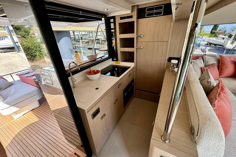  Yacht Photos Pics Modern yacht kitchen interior with wood finish, featuring a sink, stove, and cozy seating area. Prestige F4.9, 2026.