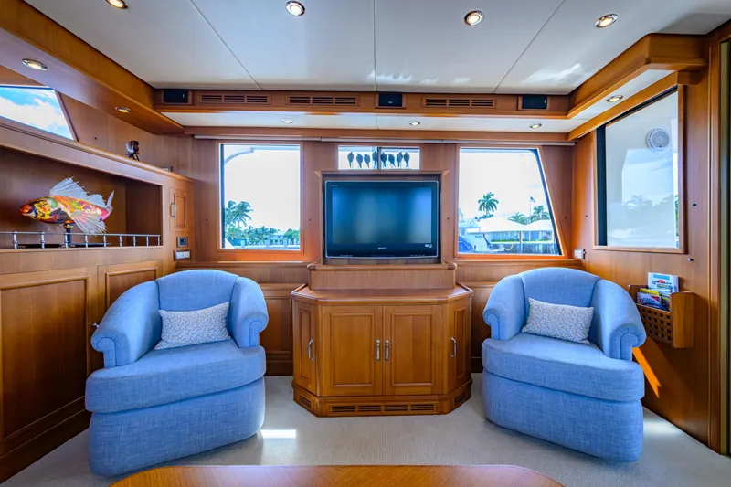 Monkey Business Yacht Photos Pics Luxurious 2007 Grand Banks 59 Aleutian RP yacht interior with blue armchairs and wooden cabinetry.