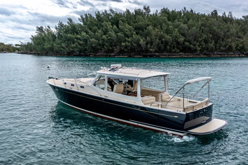 Handful Yacht Photos Pics 2014 MJM 40z yacht cruising on serene waters near a lush, forested shoreline.