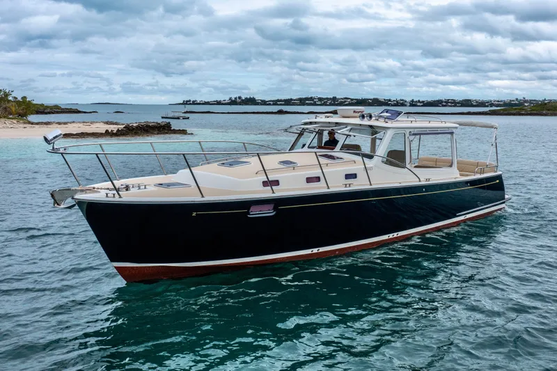 Handful Yacht Photos Pics 2014 MJM 40z yacht cruising in clear blue waters near a sandy beach.