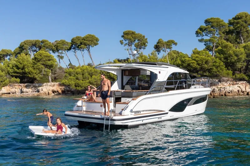  Yacht Photos Pics 2026 Marex 390 yacht with people enjoying water activities near a scenic coastline.