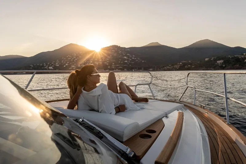  Yacht Photos Pics Woman relaxing on a 2026 Marex 390 yacht at sunset, scenic mountain backdrop.