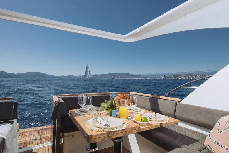  Yacht Photos Pics Luxury dining setup on Marex 390 yacht, 2026, with ocean view and sailboat in background.