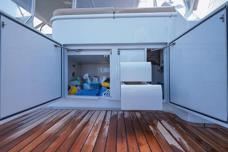 Chunda Yacht Photos Pics Open storage compartment on 1998 Merritt 48 yacht with cleaning supplies on wooden deck.