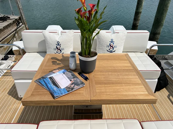  Yacht Photos Pics 2023 Pardo Yachts 38 Outboard deck with wooden table, plant, and nautical-themed cushions.