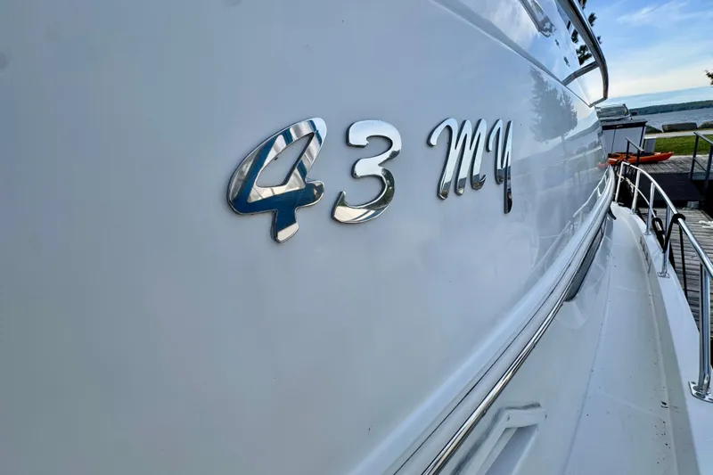 Water Music Yacht Photos Pics 2006 Carver 43 Motor Yacht with chrome lettering on the hull, docked by the water.