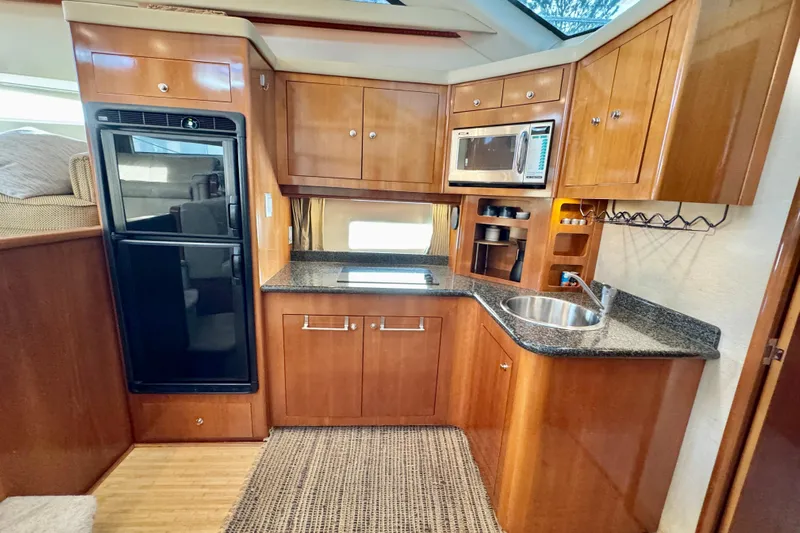 Water Music Yacht Photos Pics 2006 Carver 43 Motor Yacht kitchen with wood cabinetry, sink, microwave, and refrigerator.