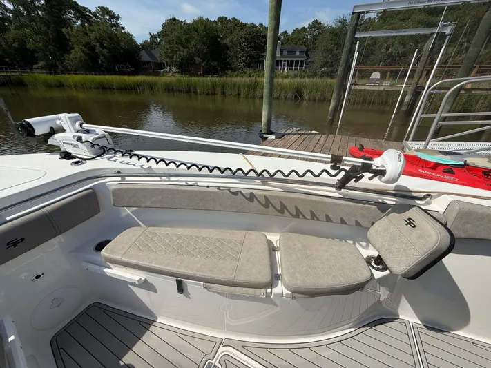  Yacht Photos Pics 2024 Sea Pro 262DLX boat interior with seating and trolling motor, docked by a serene waterfront.