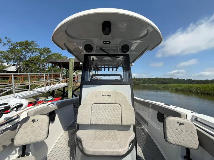  Yacht Photos Pics 2024 Sea Pro 262DLX boat interior with seating, docked by a scenic river.
