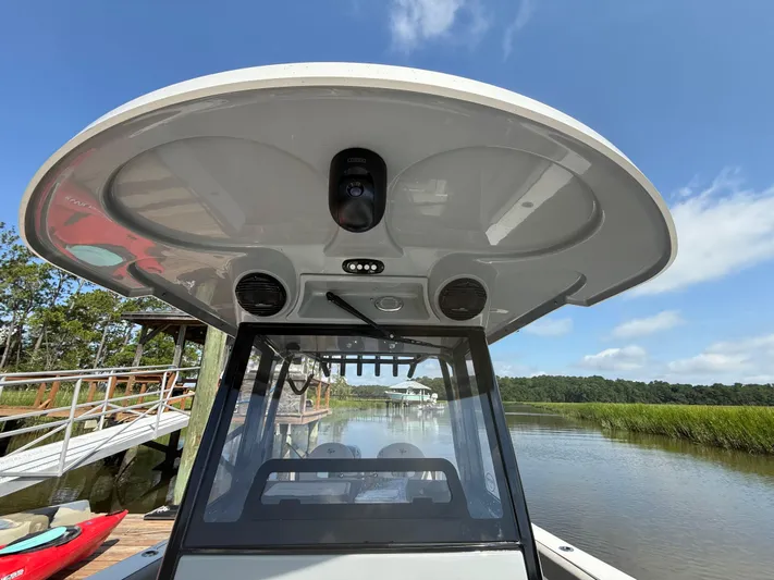  Yacht Photos Pics 2024 Sea Pro 262DLX boat with advanced canopy and speakers, docked by a serene river.