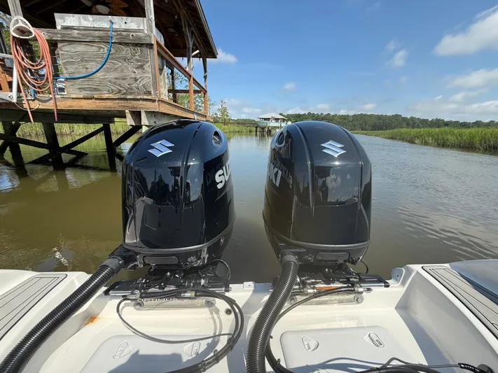  Yacht Photos Pics Twin Suzuki outboard engines on a 2024 Sea Pro 262DLX boat near a wooden dock.