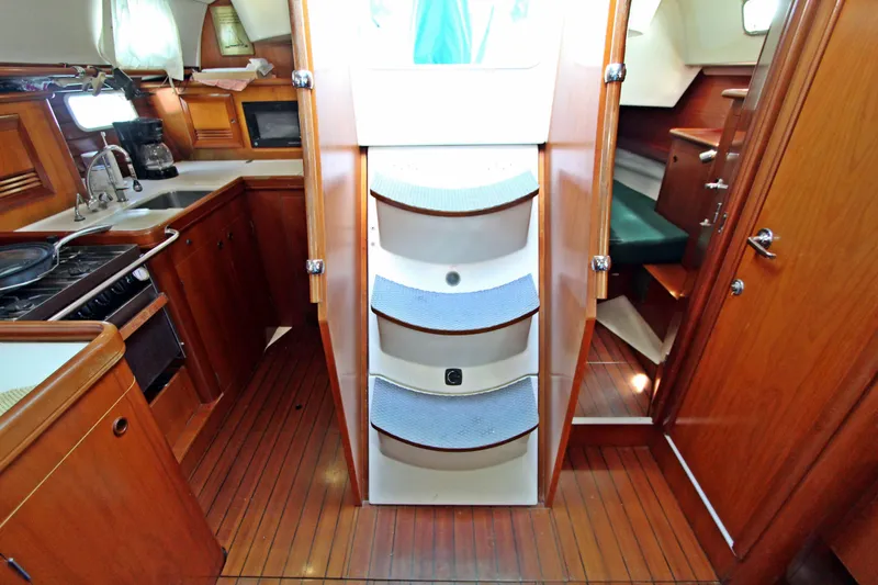  Yacht Photos Pics Interior of 2001 Beneteau Oceanis 461 sailboat, featuring wooden cabinetry and compact kitchen area.