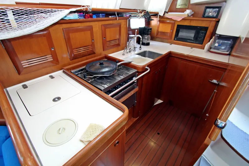  Yacht Photos Pics Interior view of 2001 Beneteau Oceanis 461 yacht kitchen with wooden cabinetry and appliances.