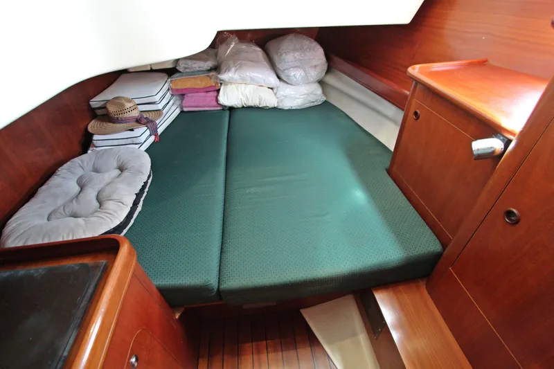 Yacht Photos Pics Cozy cabin interior of 2001 Beneteau Oceanis 461 sailboat with green mattress and wooden furnishings.