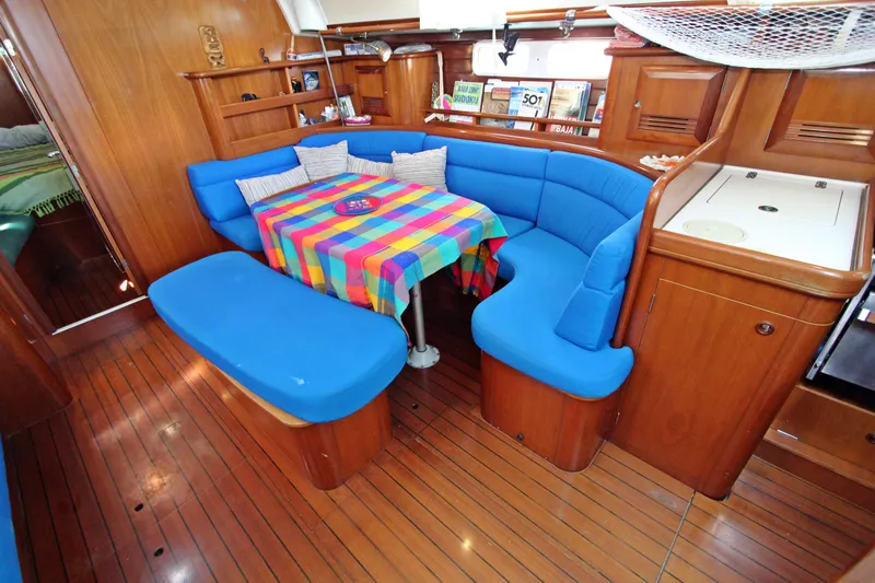  Yacht Photos Pics Interior of 2001 Beneteau Oceanis 461 yacht with blue seating and colorful tablecloth.
