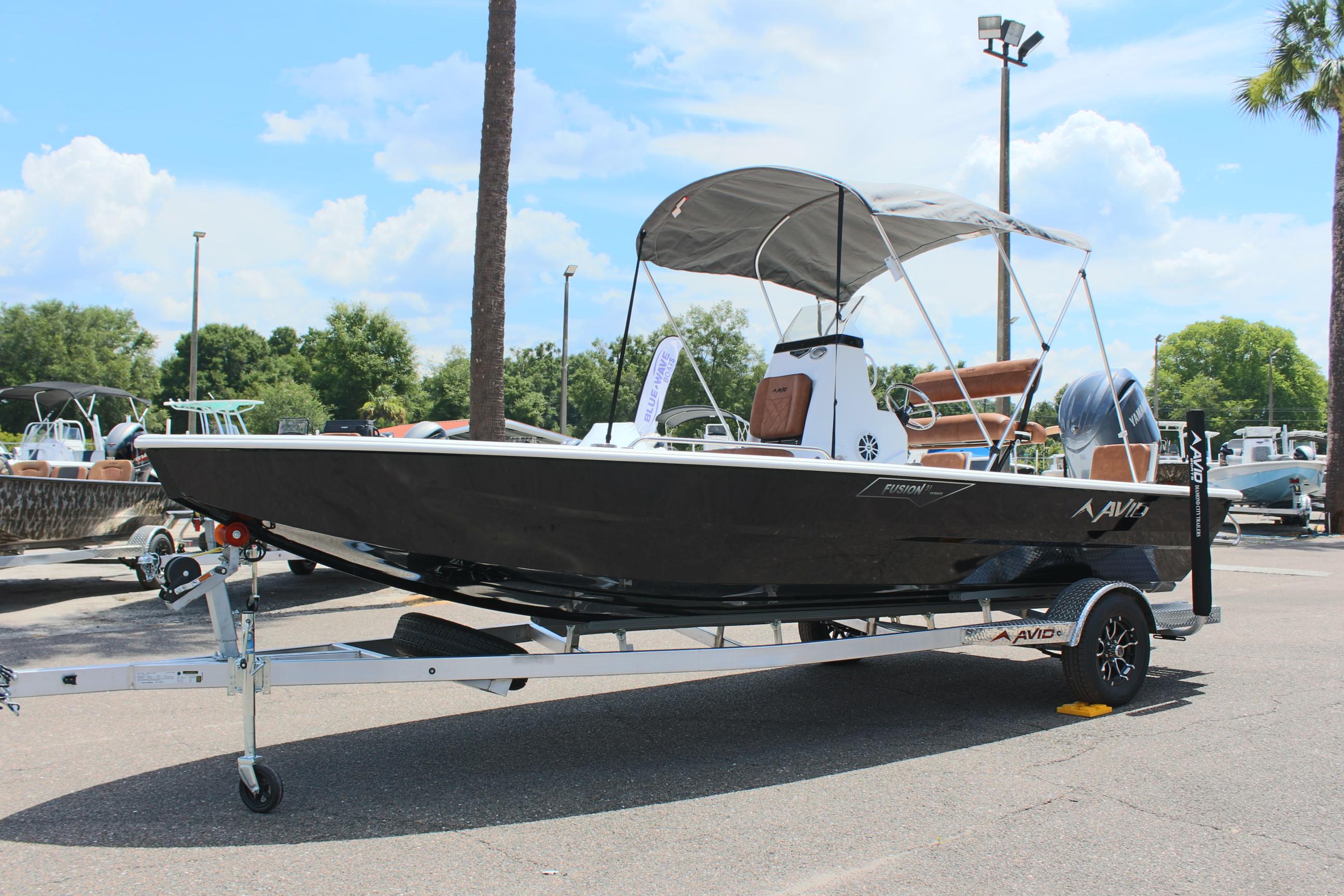 2024 Avid 21 Fusion boat on a trailer with a canopy in a marina.