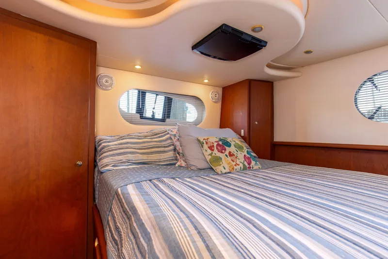  Yacht Photos Pics Interior of 2005 Silverton 43 Motor Yacht bedroom with striped bedding and decorative pillows.