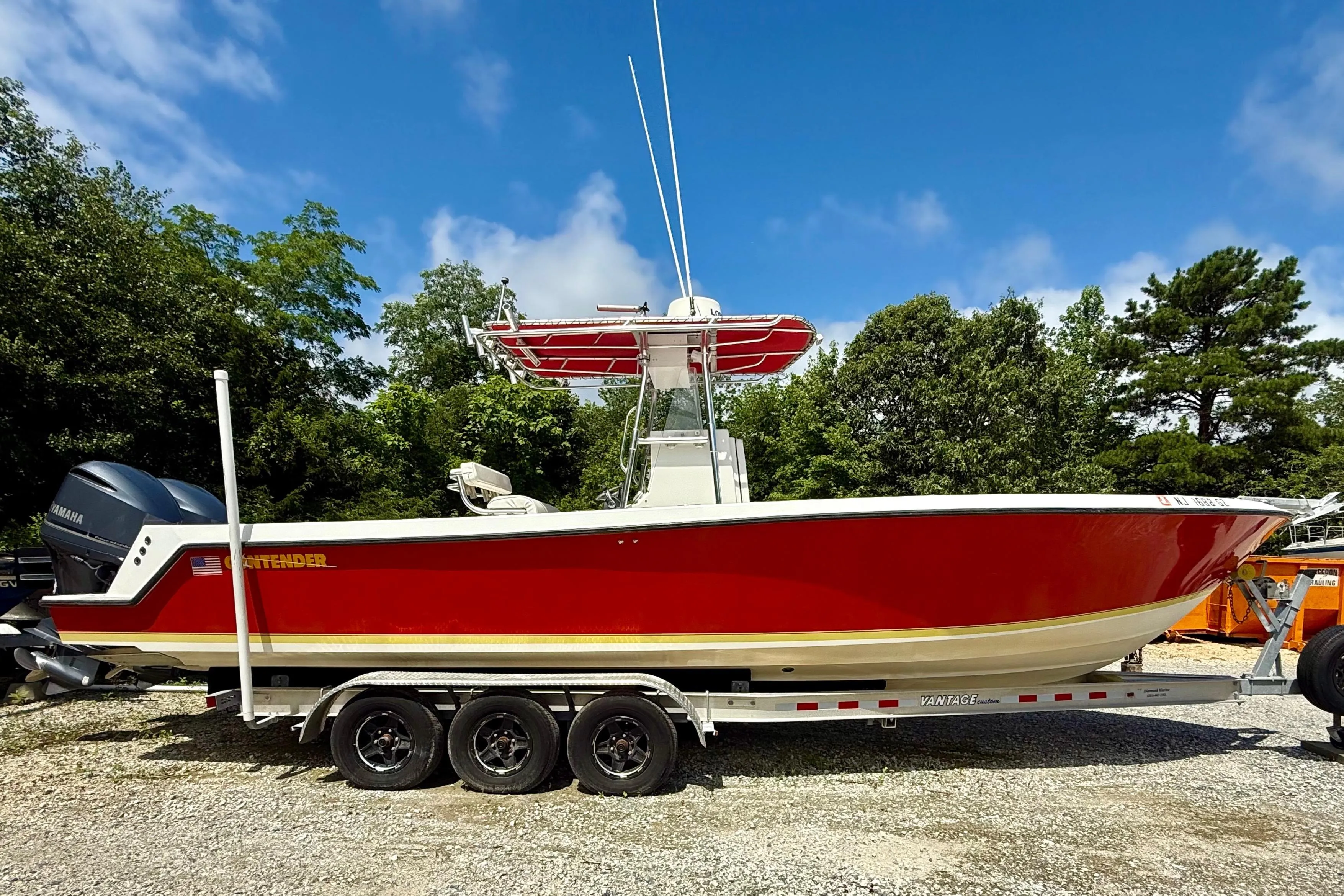 2002 Contender 27 Tournament boat with red hull on trailer, parked outdoors.