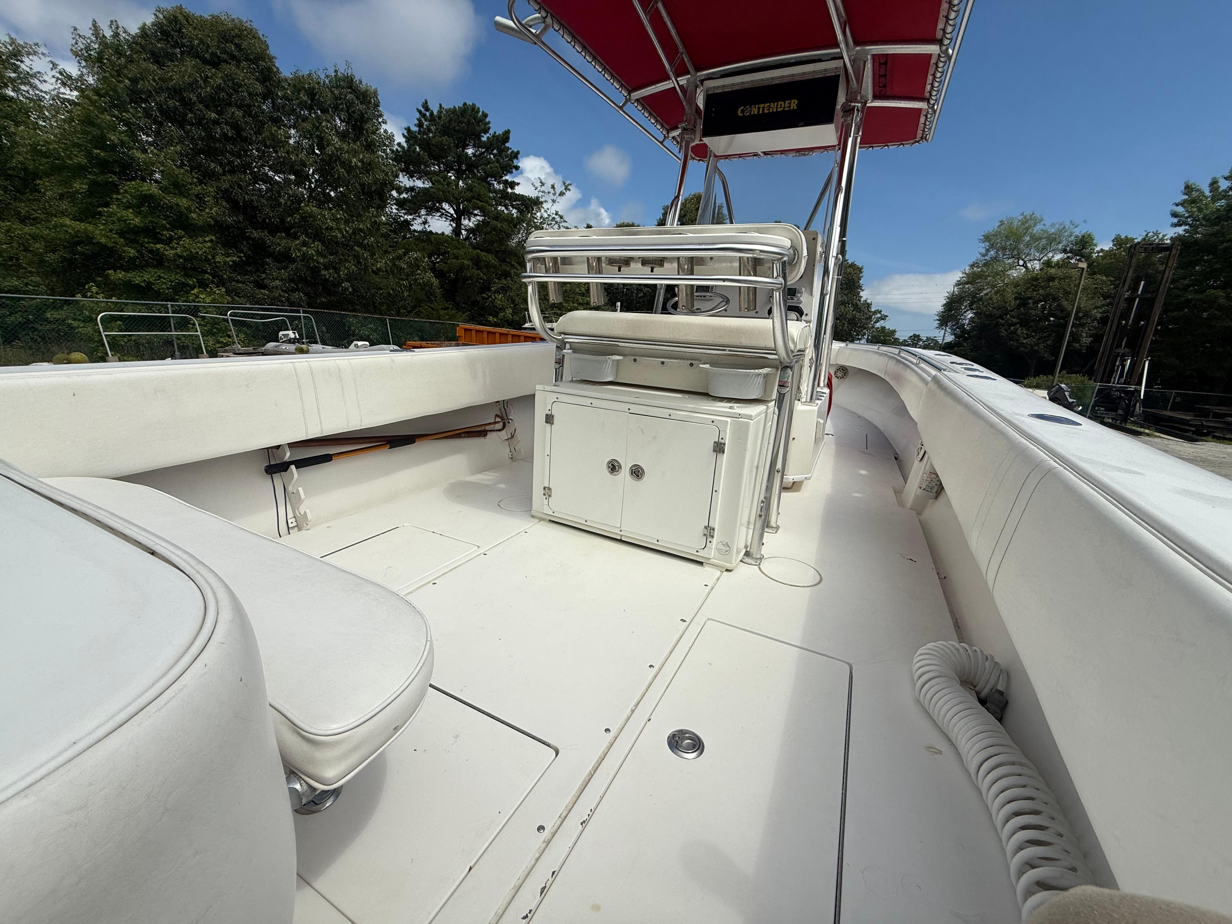 2002 Contender 27 Tournament boat interior with seating and storage, under a red canopy.