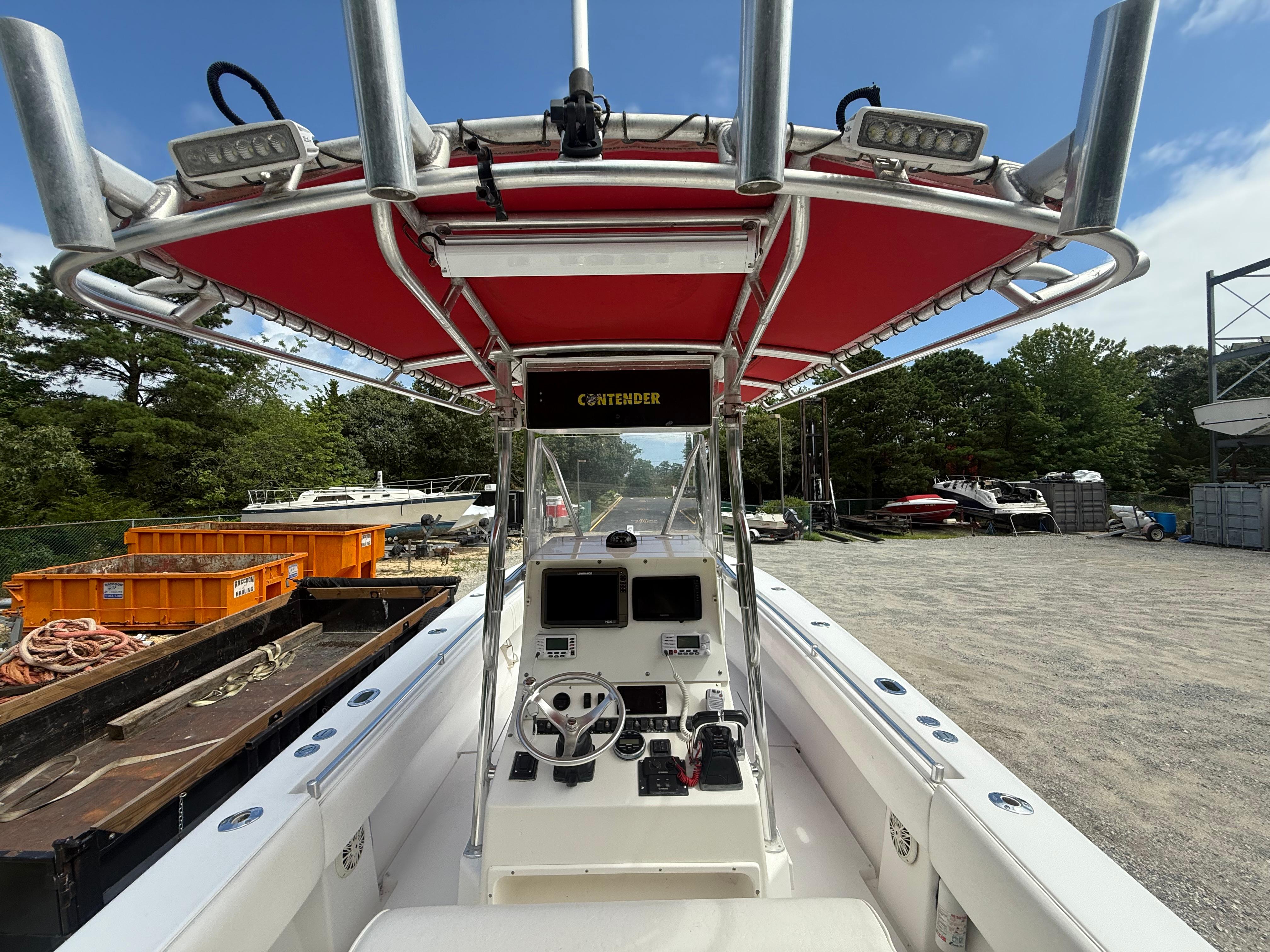 2002 Contender 27 Tournament boat with red canopy, parked outdoors on gravel.