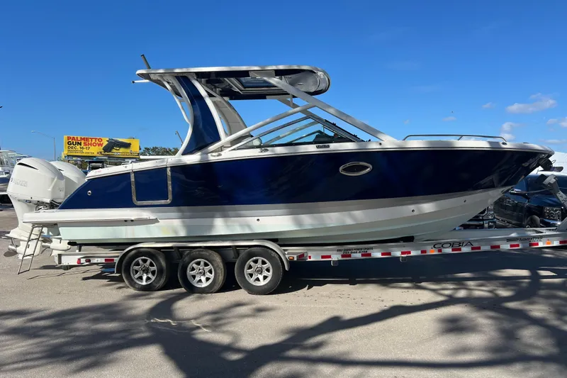  Yacht Photos Pics 2020 Chaparral 280 OSX boat on trailer, blue and white design, clear sky background.