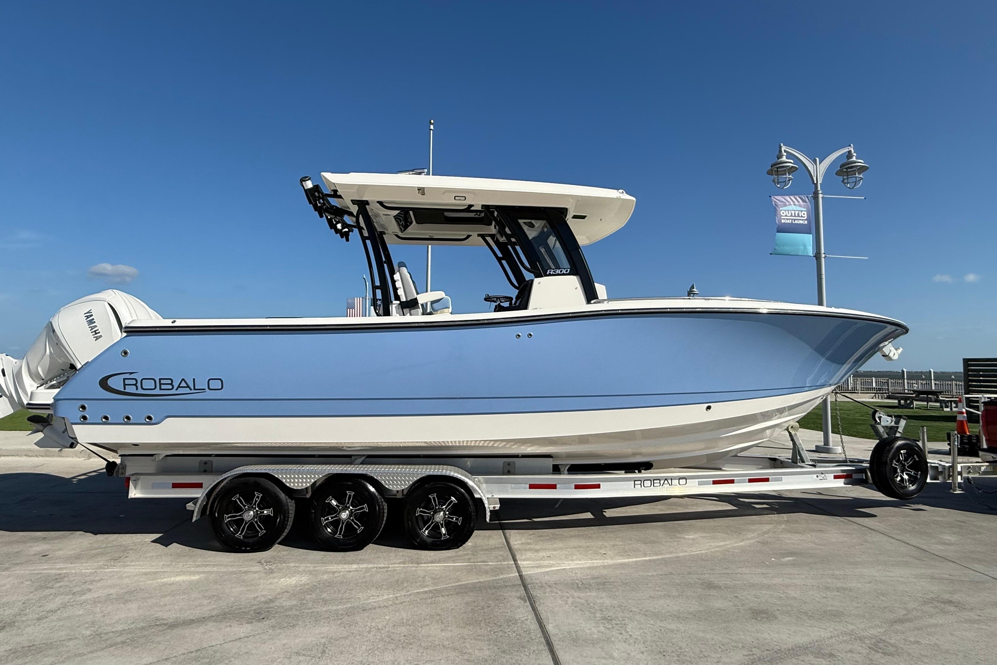 2025 Robalo R300 Center Console boat on trailer, side view, clear sky background.