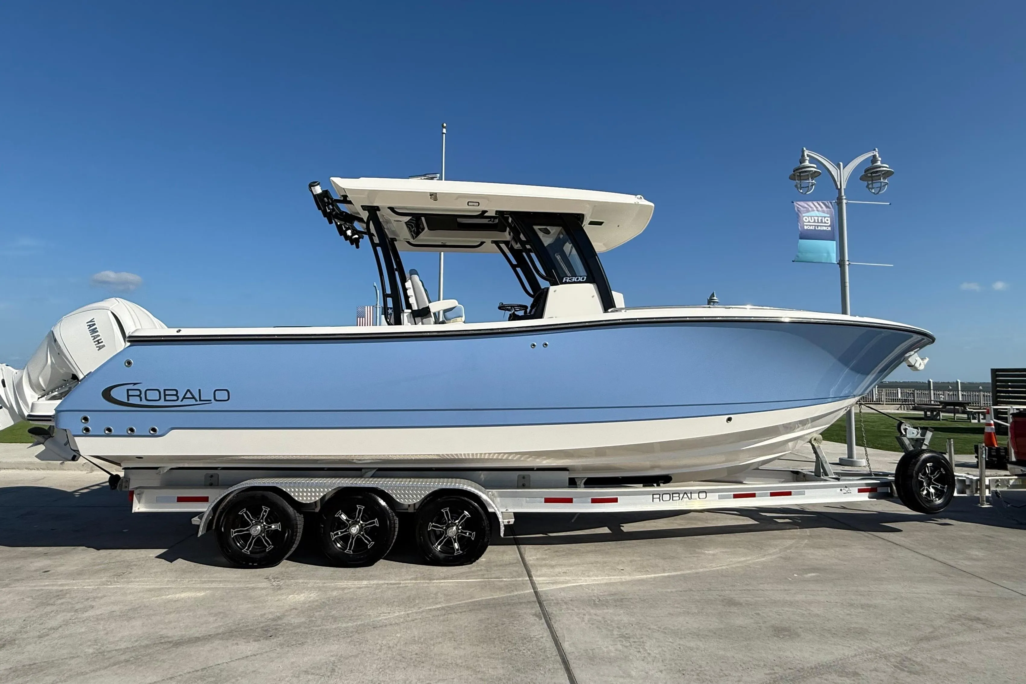 2025 Robalo R300 Center Console boat on trailer, side view, clear sky background.