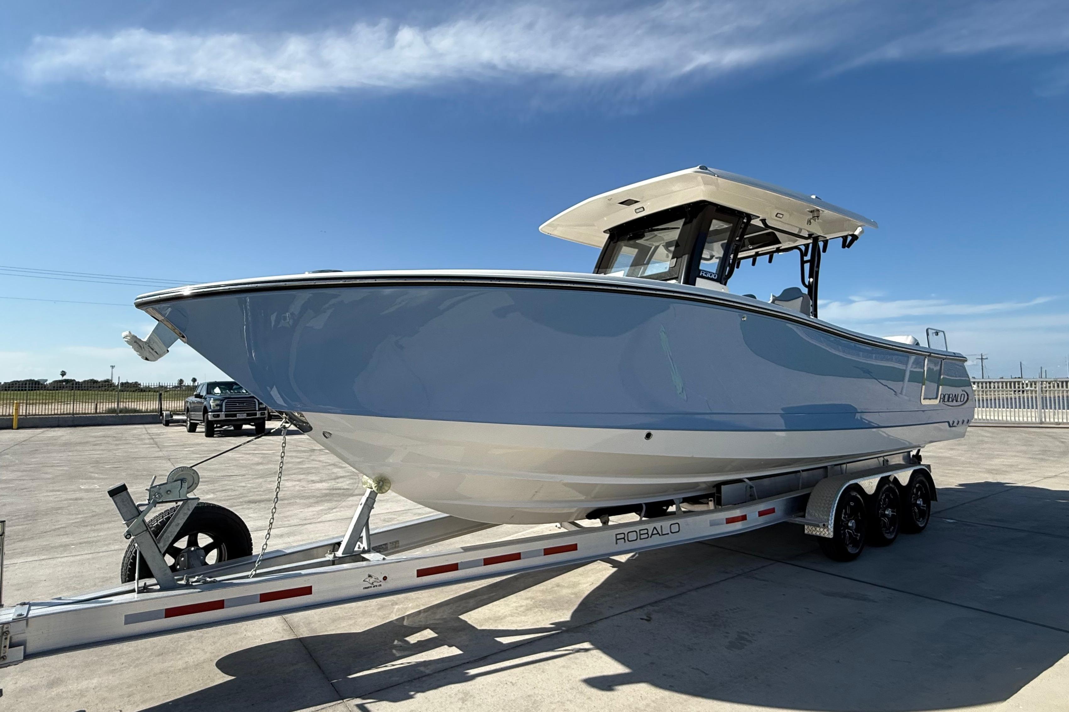 2025 Robalo R300 Center Console boat on trailer under clear blue sky.